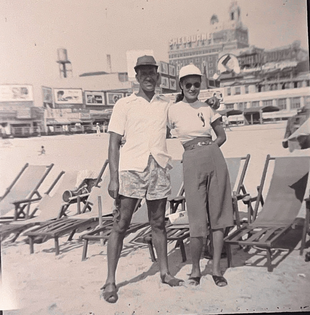 man and woman posing for picture with beach chairs behind them